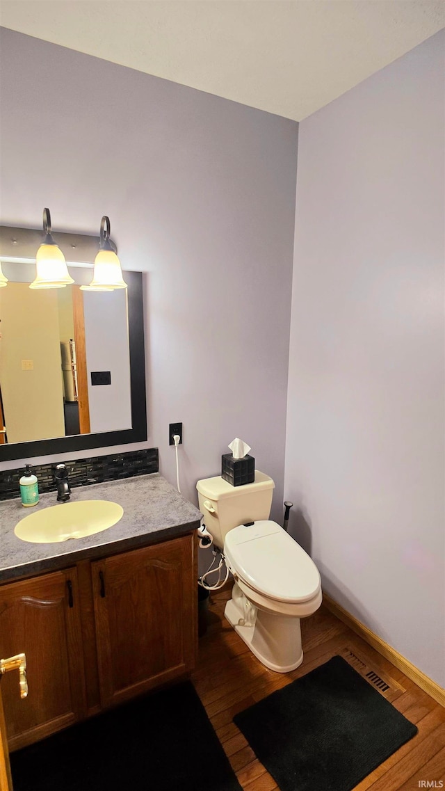 bathroom with wood-type flooring, vanity, and toilet