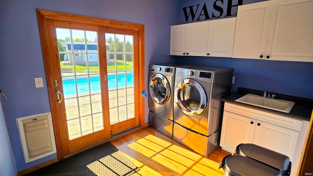 laundry room featuring cabinets, light hardwood / wood-style flooring, washing machine and clothes dryer, and sink