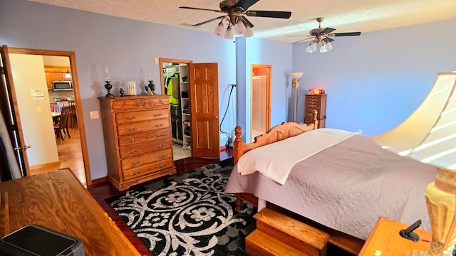 bedroom featuring a closet, ceiling fan, a walk in closet, and hardwood / wood-style floors