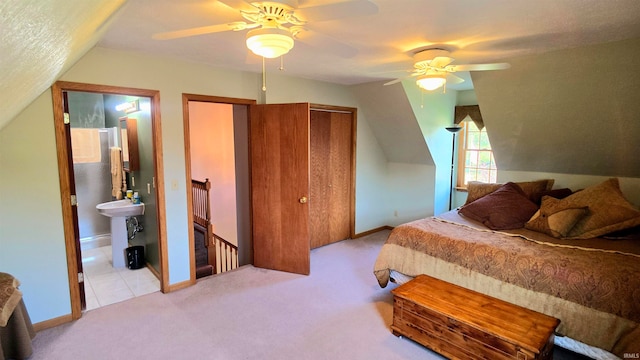 bedroom featuring connected bathroom, vaulted ceiling, light carpet, and ceiling fan