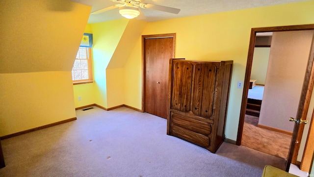 interior space featuring ceiling fan, a textured ceiling, lofted ceiling, and light carpet