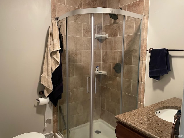 bathroom with vanity, toilet, and a shower with door