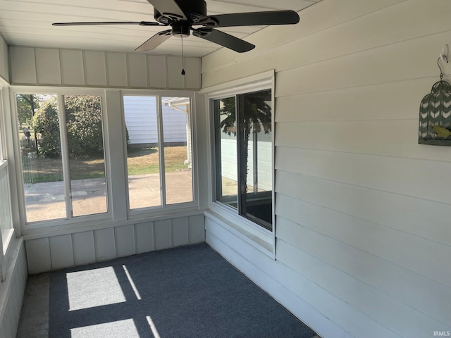 unfurnished sunroom featuring ceiling fan and plenty of natural light