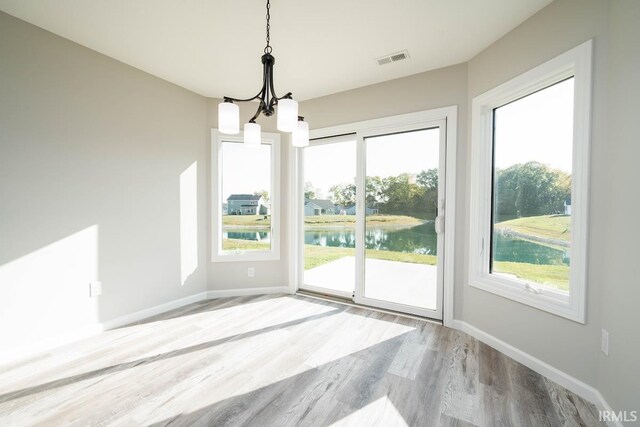 interior space featuring an inviting chandelier, a water view, and hardwood / wood-style floors