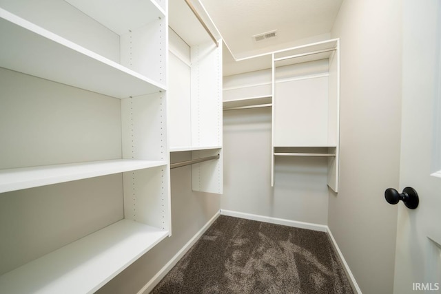 walk in closet with dark carpet