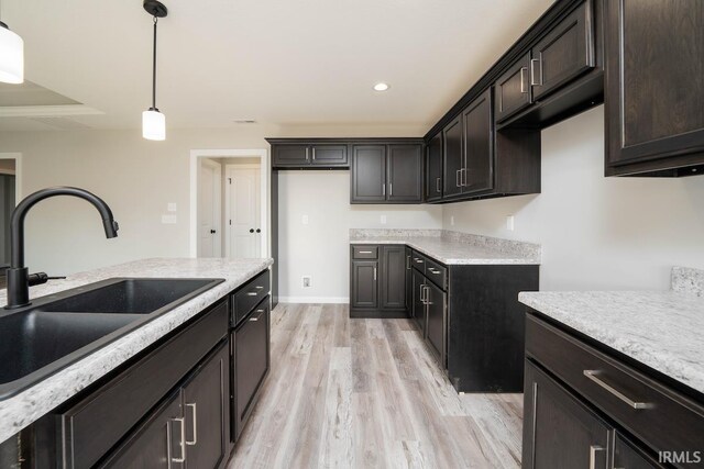 kitchen featuring pendant lighting, dark brown cabinets, light hardwood / wood-style floors, and sink