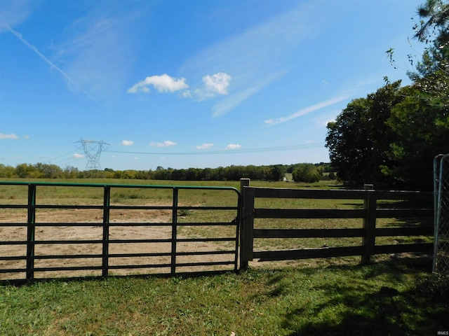 view of gate with a yard and a rural view