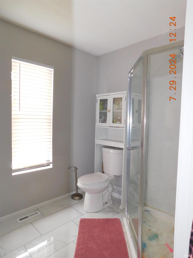 bathroom featuring a wealth of natural light, tile patterned flooring, walk in shower, and toilet