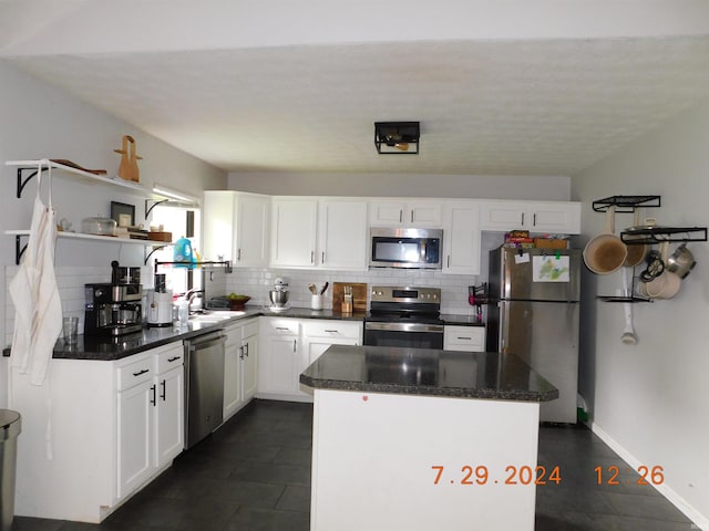 kitchen featuring decorative backsplash, white cabinetry, appliances with stainless steel finishes, and a kitchen island