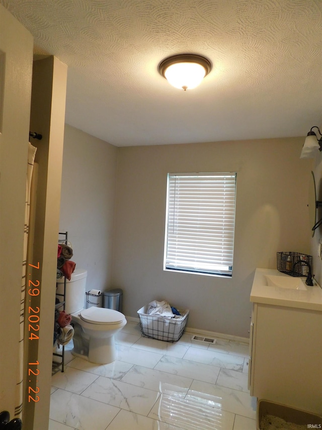 bathroom with a textured ceiling, vanity, and toilet