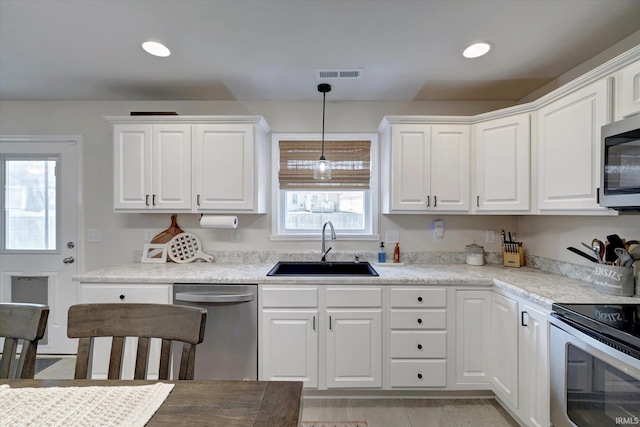 kitchen featuring appliances with stainless steel finishes, hanging light fixtures, sink, and white cabinetry