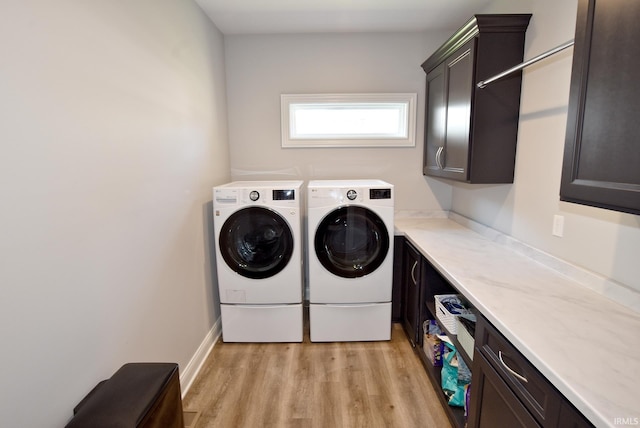 laundry area featuring washer and dryer, cabinet space, and light wood-style floors