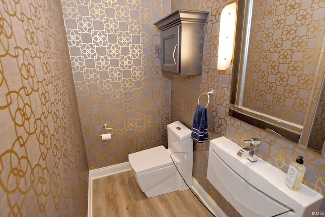 bathroom featuring a sink, toilet, baseboards, and wood finished floors