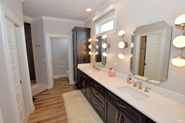 bathroom featuring a shower, hardwood / wood-style floors, ornamental molding, vanity, and toilet