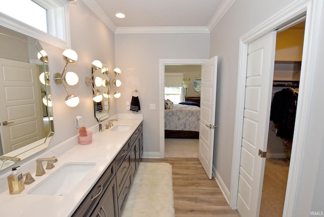full bath featuring wood finished floors, ensuite bath, double vanity, a sink, and crown molding