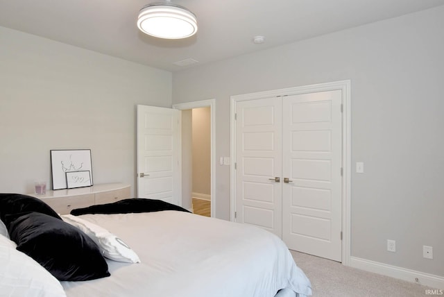 carpeted bedroom with a closet and baseboards