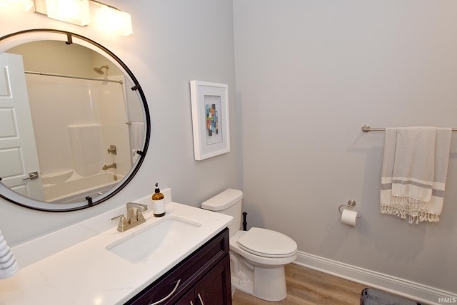 bathroom featuring toilet, shower / washtub combination, wood finished floors, baseboards, and vanity