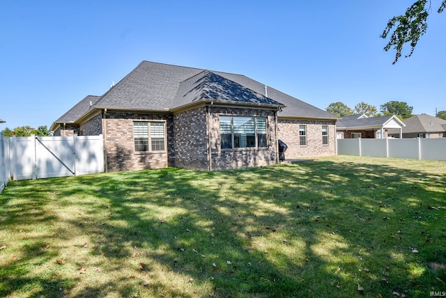 back of property featuring a lawn, brick siding, and a fenced backyard