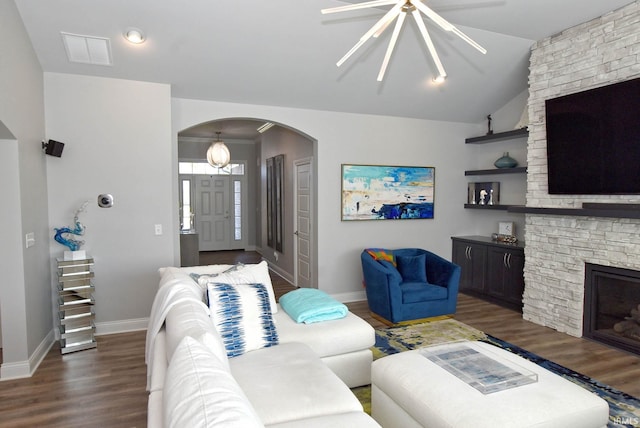 living room featuring wood finished floors, visible vents, a fireplace, arched walkways, and vaulted ceiling