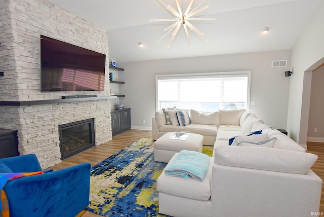 living area featuring vaulted ceiling, light wood-style flooring, a notable chandelier, and visible vents