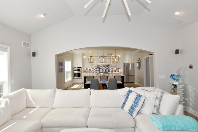 living room with a notable chandelier, lofted ceiling, and hardwood / wood-style floors