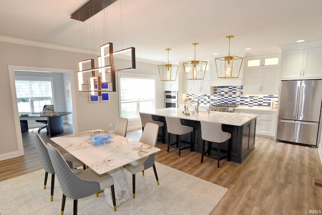 dining area featuring a healthy amount of sunlight, light wood-type flooring, and crown molding