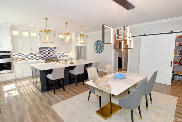 dining room with recessed lighting, light wood-type flooring, a barn door, and ornamental molding