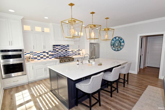 kitchen featuring light wood-style flooring, a kitchen breakfast bar, appliances with stainless steel finishes, light countertops, and decorative backsplash