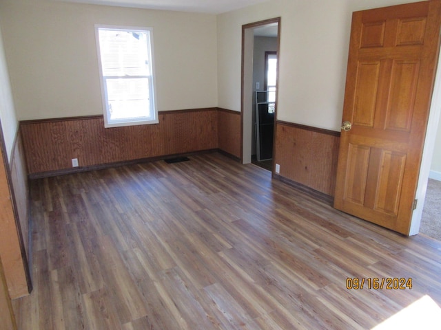 empty room with wood walls and dark wood-type flooring