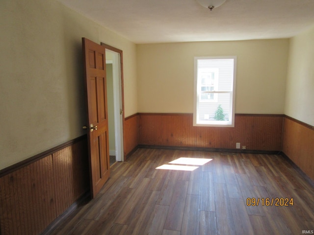 unfurnished room featuring wood walls and dark hardwood / wood-style flooring