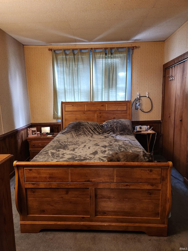 carpeted bedroom featuring a textured ceiling, wood walls, and a closet