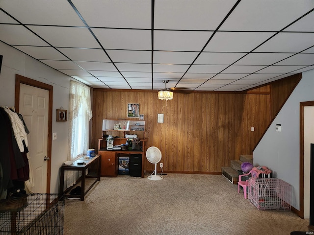 interior space featuring a drop ceiling, wooden walls, and carpet floors