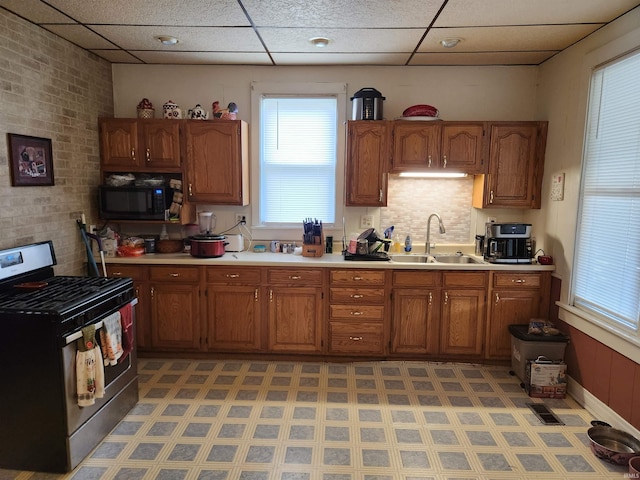 kitchen with a drop ceiling, gas range, and sink