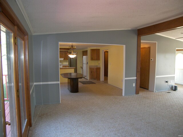 spare room featuring light carpet, vaulted ceiling, a textured ceiling, and ornamental molding