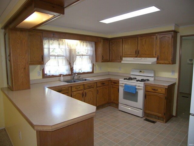 kitchen with kitchen peninsula, sink, and white gas stove