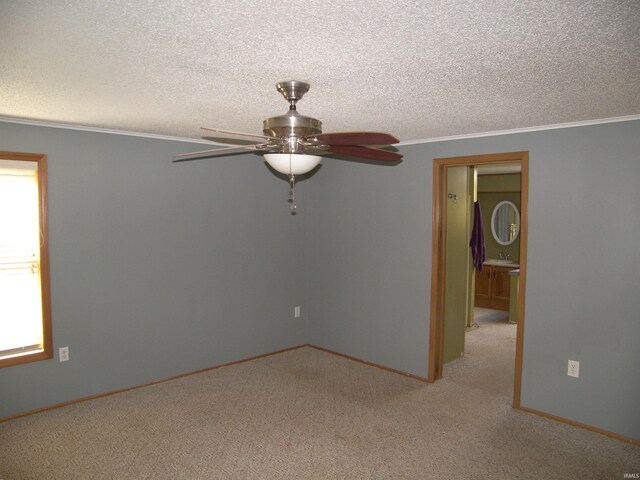 unfurnished room featuring a textured ceiling, sink, light colored carpet, ornamental molding, and ceiling fan