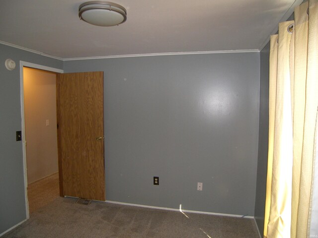 empty room featuring crown molding and carpet flooring