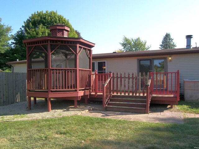 rear view of house with a gazebo, a deck, and a lawn