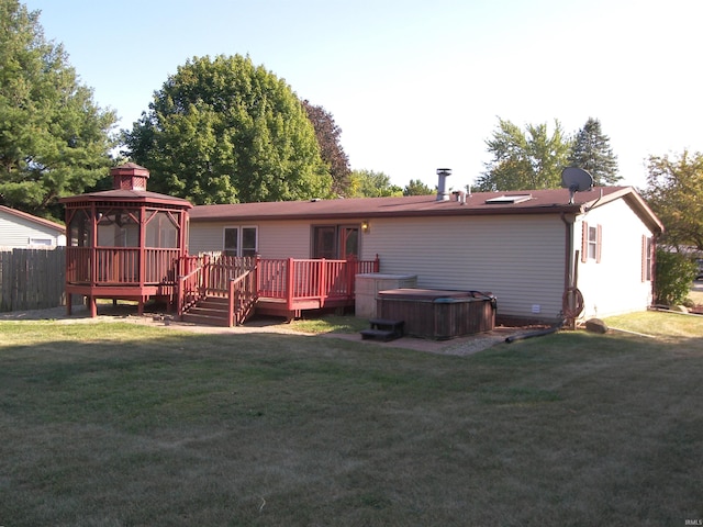 back of property with a gazebo, a yard, a hot tub, and a deck