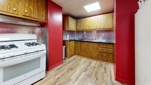 kitchen with light hardwood / wood-style floors, sink, ventilation hood, backsplash, and white range with gas cooktop