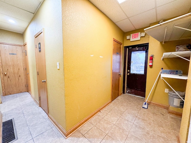 corridor with a paneled ceiling and tile patterned flooring