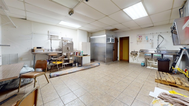 miscellaneous room featuring a drop ceiling, light tile patterned flooring, and a wall mounted AC