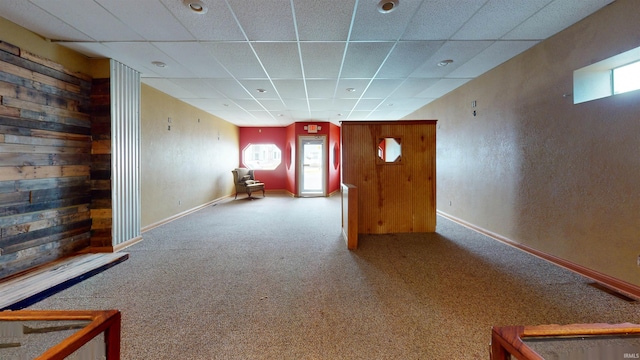 unfurnished room with wood walls, a paneled ceiling, and carpet flooring