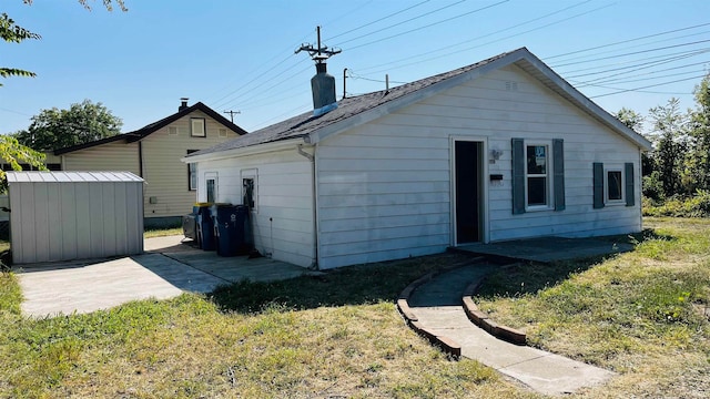 back of property with a storage shed and a lawn