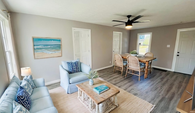 living room with ceiling fan and dark wood-type flooring