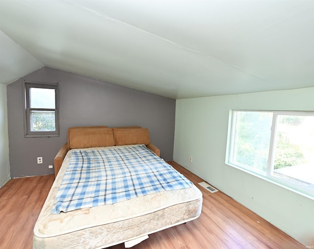 bedroom with light hardwood / wood-style flooring, lofted ceiling, and multiple windows