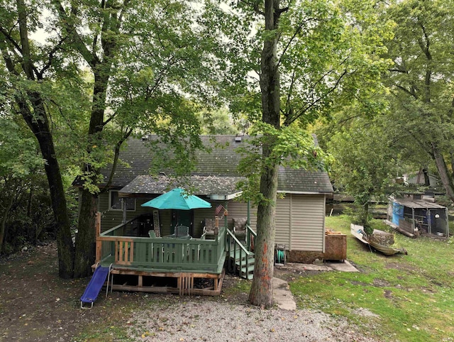 back of property featuring a storage unit and a deck