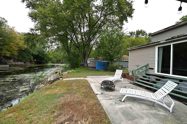 view of yard with a patio, a fire pit, a storage unit, and a water view