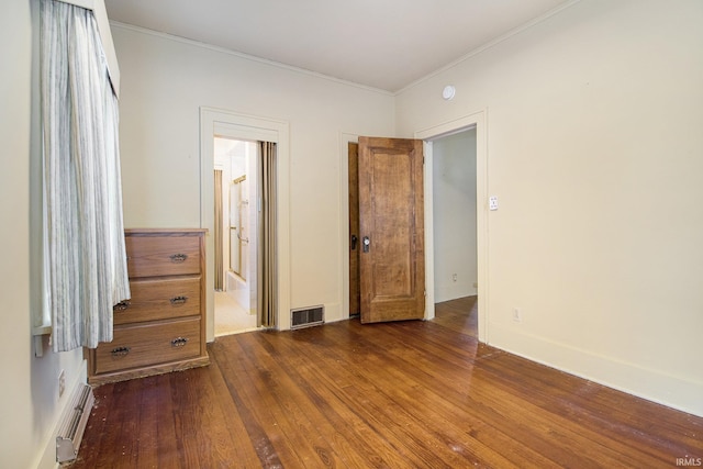 unfurnished bedroom with baseboard heating, crown molding, and dark hardwood / wood-style flooring