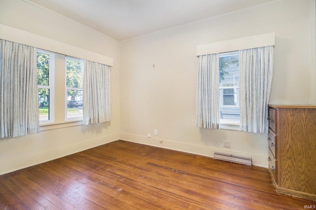 empty room with ornamental molding, wood-type flooring, and baseboard heating